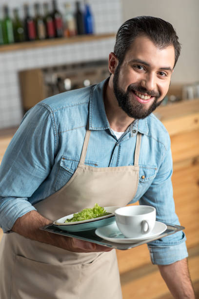 istock Positive responsible waiter smiling while taking the dirty dishes 887677914