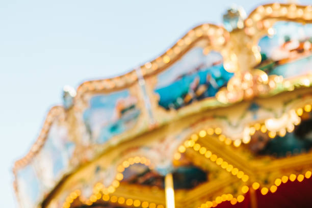 Old fashioned carousel at night on Christmas market in amusement park.\n\nDefocused illuminated abstract background with multi colored. Blurred merry-go-round in a funfair background.