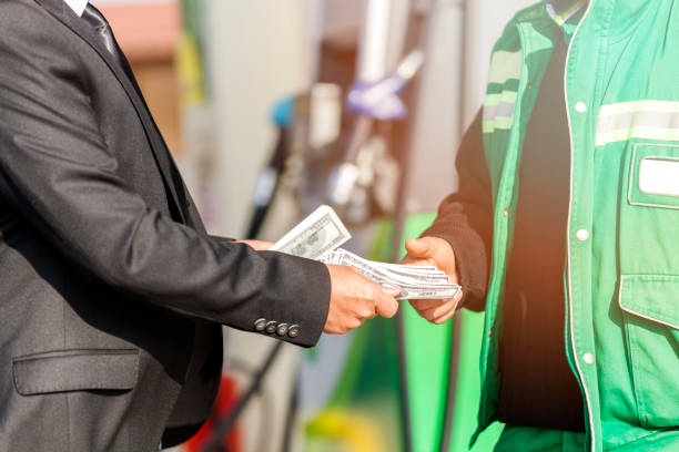 uomo d'affari paga in contanti alla stazione di servizio - gasoline fuel pump women currency foto e immagini stock
