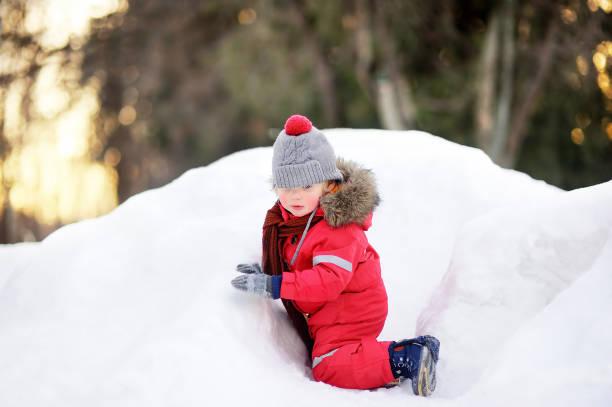 istock Little boy in red winter clothes having fun with fresh snow 887704178