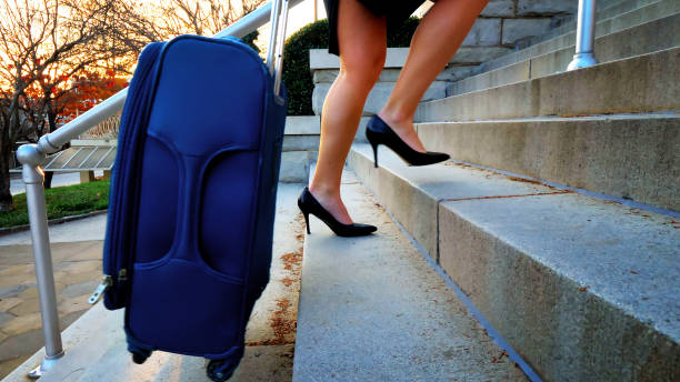 istock Woman outside pulling suitcase up stairs. 887711446