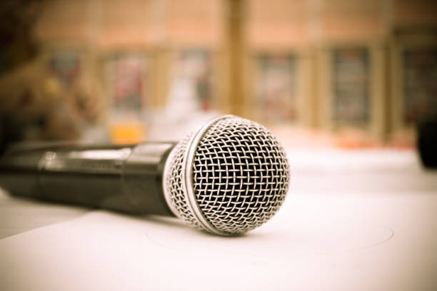 istock Microphone on abstract blurred of front podium and speech in seminar room or speaking conference hall light, Event meeting bokeh background, black and white tone 887731846