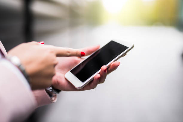 Young businesswoman using her touch screen phone. Close-up.
