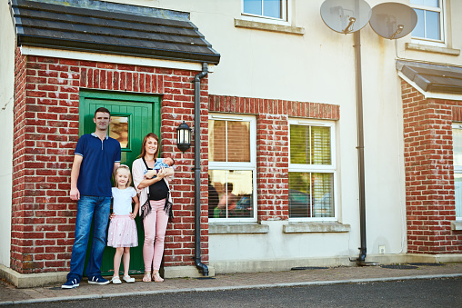 Portrait of a cheerful young family grouped together while looking at the camera outside