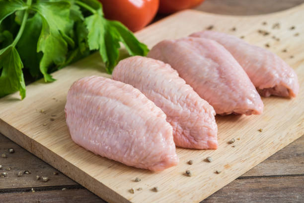 istock Raw chicken wings on wooden cutting board 887762456