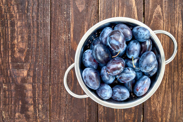 istock Blue plums in rustic colander on old wooden table. Organic food. Copy space, top view 887781452