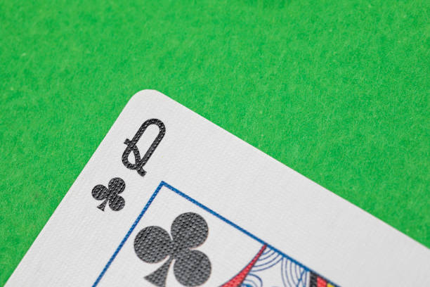 Close up shot of a playing card on a green surface, queen of clubs