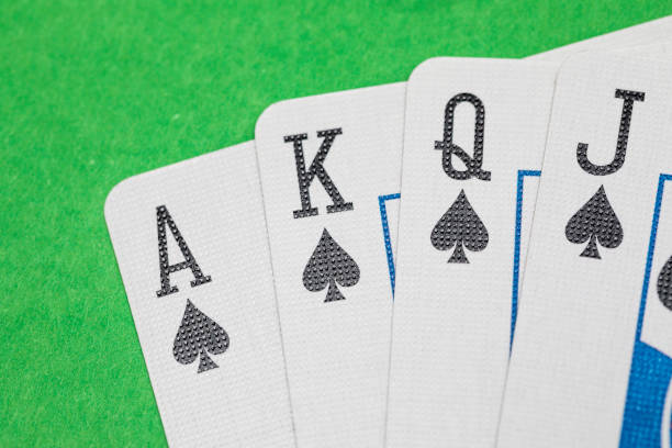 Close up shot of playing cards on a green surface, set of spades. Jack, Queen, King, Ace