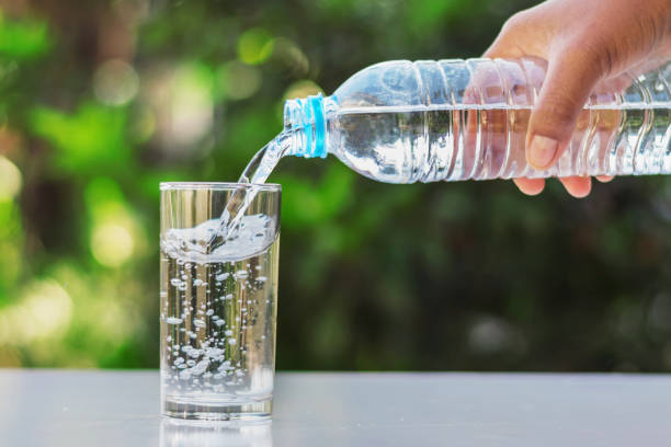 istock hand pouring drinking water into glass form bottle on table 887798452