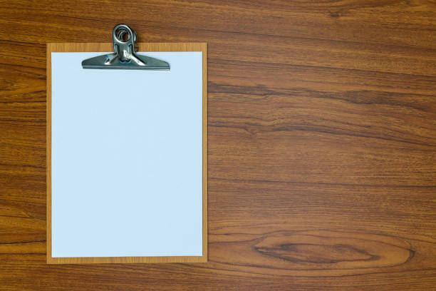 istock clipboard with blank white paper sheet on wood table top view with copy space. 887806706