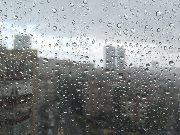 istock rain drops on windowpane against buildings 887807080