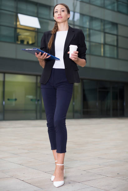 gerente de oficina de la mujer está examinando documentos y tomando café - success signing businesswoman serious fotografías e imágenes de stock