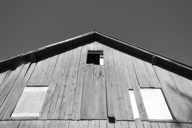 Old agricultural building with missing timber and a rusted roof stands exposed in a wide rural field