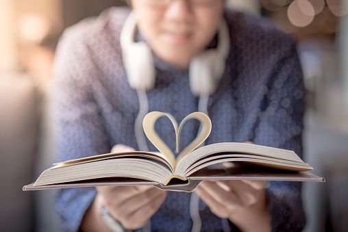Young Asian happy man holding book with heart shape page folded in the centre. love and valentine concepts
