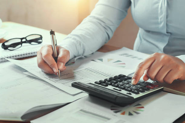 istock businesswoman working in office on desk using calculator and pen 887860348