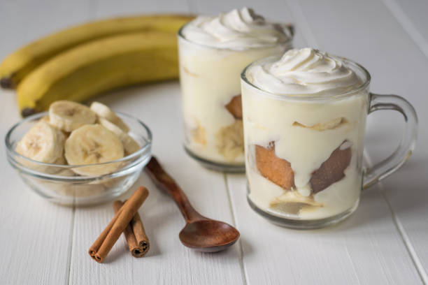 istock Banana dessert with whipped cream and biscuit on a white wooden rustic table. 887860588