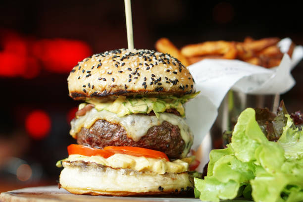 istock Homemade double cheese burger assorted with wagyu beef, tomato, onion, cheddar cheese, lettuce, spicy sauce served with french fries and salad. 887865920