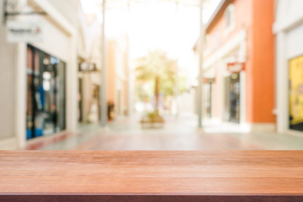 istock Wooden board empty table blurred shopping mall background. Perspective brown wooden table blur in department store background - can be used for display or montage your products. Mock up for of product 887870796