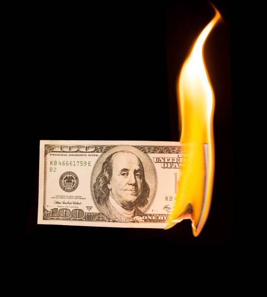 istock a hundred dollars burn in a fire on a black background 887880256