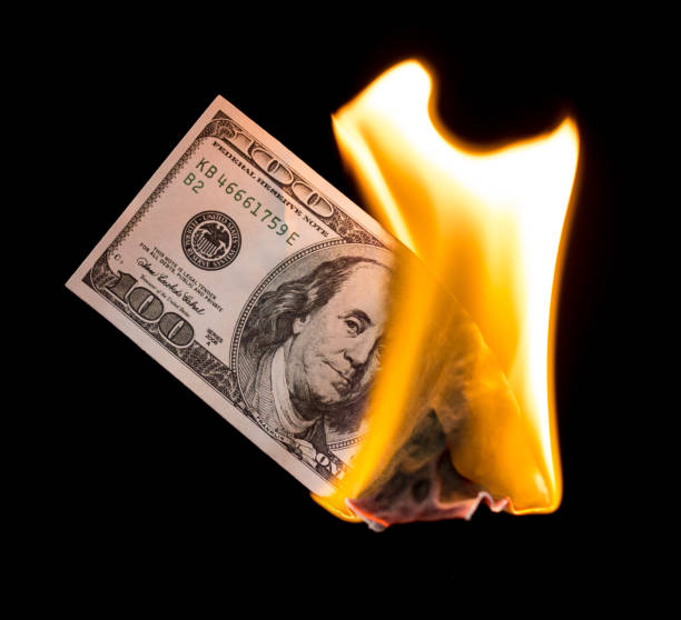 istock a hundred dollars burn in a fire on a black background 887880428