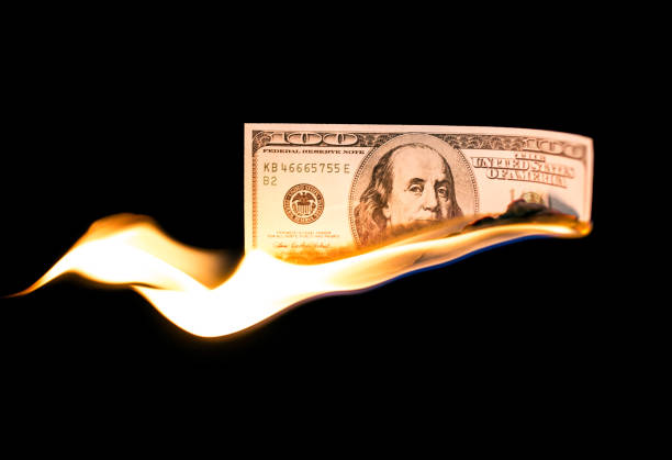 istock a hundred dollars burn in a fire on a black background 887880538