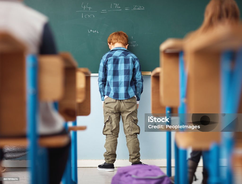 It's no fun feeling like a loser Rear view shot of an elementary school boy leaning with his head on the chalkboard in class Child Stock Photo