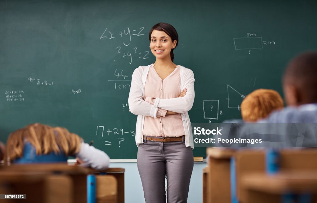 Here to further enrich so many eager minds Portrait of a young female teacher standing in a classroom Teacher Stock Photo