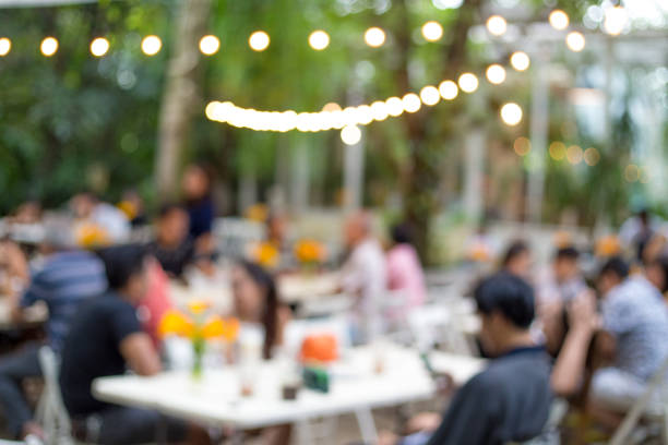 Blurred background of restaurant with unrecognizable silhouettes of people sitting at the table.