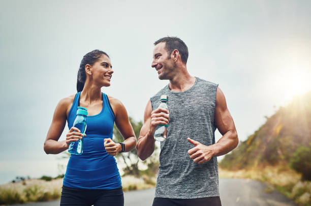 Quench your thirst then get back to it Shot of a young attractive couple training for a marathon outdoors quench your thirst pictures stock pictures, royalty-free photos & images