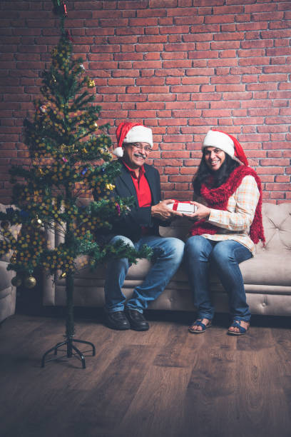 istock indian senior couple exchanging christmas gift while sitting on sofa 887924212