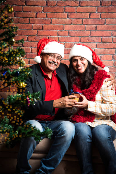 istock indian senior couple exchanging christmas gift while sitting on sofa 887924548