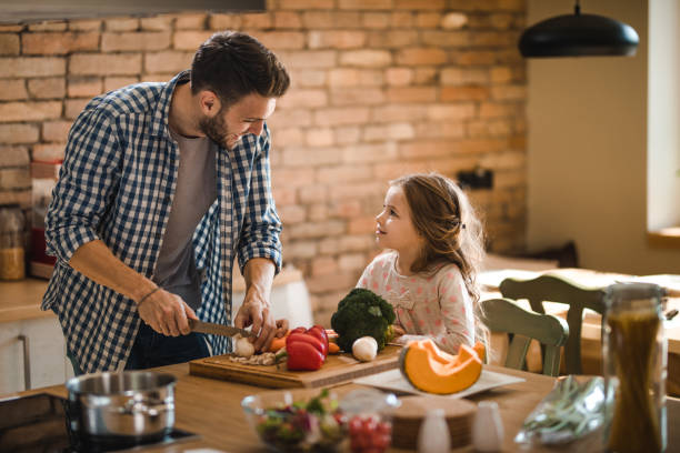 istock Happy single father talking to his small daughter while preparing food together. 887938252