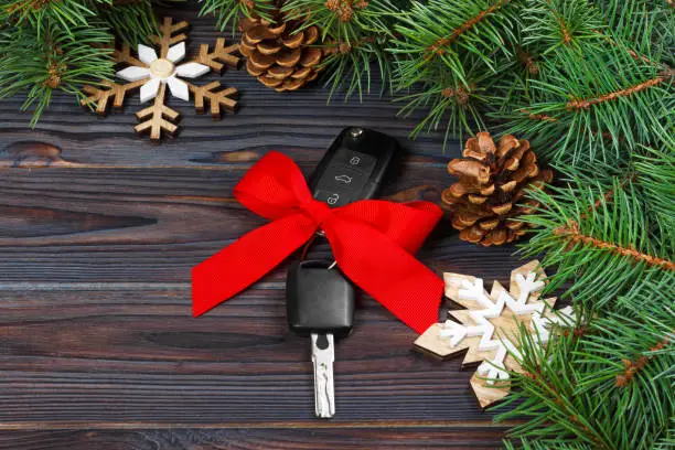 Photo of Close-up view of car keys with red bow as present on wooden background