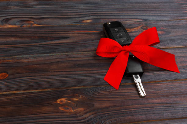 istock Car key with colorful bow on wooden background 887940556
