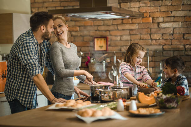 istock Happy family cooperating while making lunch in the kitchen. 887942520