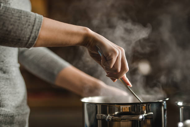 nicht erkennbare frau rühren suppe in einem topf beim mittagessen zu machen. - preparing food stock-fotos und bilder