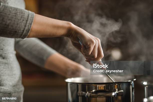 Foto de Irreconhecível Mulher Mexendo A Sopa Em Uma Panela Ao Fazer O Almoço e mais fotos de stock de Cozinhar