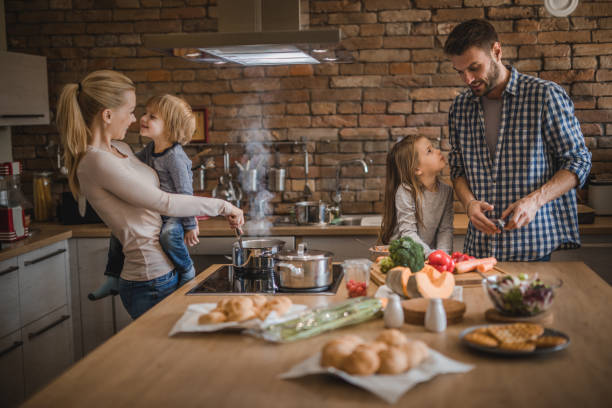 istock Young smiling parents enjoying while preparing lunch with their kids in the kitchen. 887945206