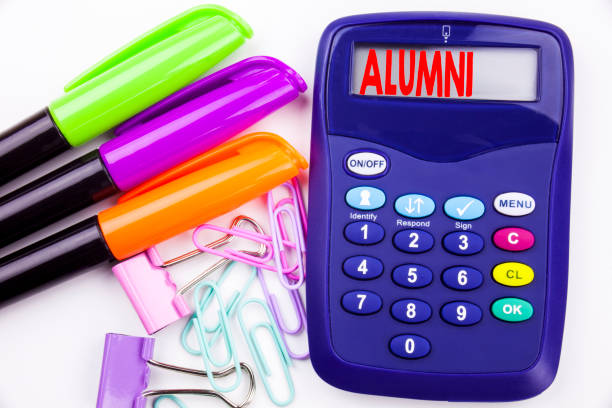 istock Writing word Alumni Former Students text in the office with surroundings such as marker, pen writing on calculator. Business concept for Celebration Education Ending white background with copy space 887954428