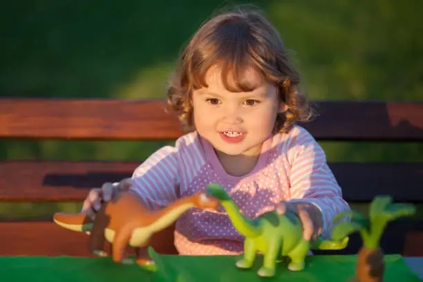 Photo of Toddler kid playing with a toy dinosaur.