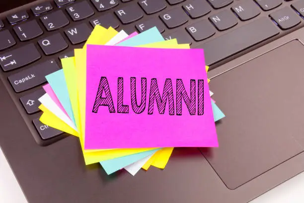 Photo of Writing Alumni Former Students text made in the office close-up on laptop computer keyboard. Business concept for Celebration Education Ending Workshop on the black background with copy space