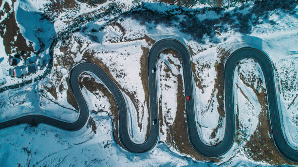 Aerial view of red car on Julier pass in Switzerland Scenic aerial view of red car on Julier pass in Switzerland in winter drone point of view road stock pictures, royalty-free photos & images