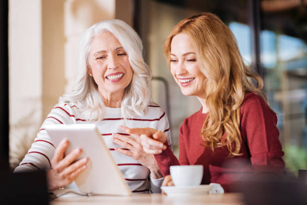istock Positive friendly women laughing while looking at the screen of a tablet 888001322