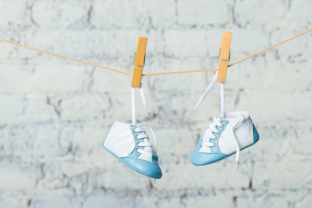 istock Baby blue shoes on a rope against a white brick wall 888004120