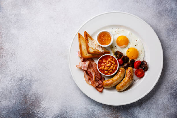 English breakfast English breakfast with fried egg, sausage, bacon, beans and toast on white background copy space english breakfast stock pictures, royalty-free photos & images