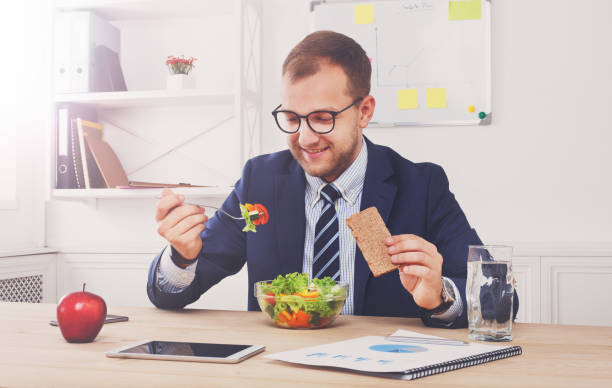 istock Man has healthy business lunch in modern office interior 888018878