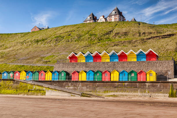 Beach Huts Whiby Yorkshire England Rows of colorful beach huts on the promenade at Whitby Sands, Whitby, North Yorkshire, England, UK, on a beautiful sunny morning in spring. beach hut photos stock pictures, royalty-free photos & images