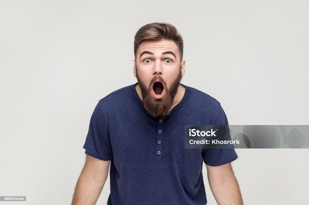 Unbelievable news! Young adult man open mouth and shocked Unbelievable news! Young adult crazy man with opened mouth looking at camera. Studio shot, gray background Surprise Stock Photo