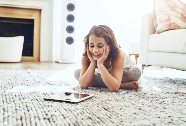 Entertaining her curious mind Shot of a cute little girl using a digital tablet while relaxing at home free girl download stock pictures, royalty-free photos & images