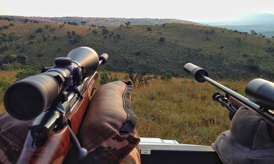 The view of a hunter over the hunting grounds with his rifles and equipment.